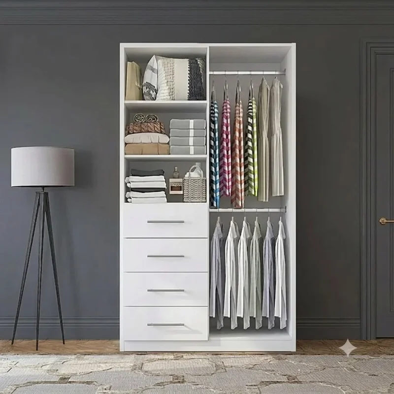 Armario blanco moderno de dos secciones en un ambiente elegante de dormitorio. La sección izquierda tiene repisas superiores con artículos del hogar, cuatro cajones centrales y un espacio inferior para zapatos. La sección derecha tiene tubos dobles para colgar ropa, con camisas y pantalones visibles. Una lámpara de trípode gris y una alfombra gris completan la escena. El armario es de 3Vetas.